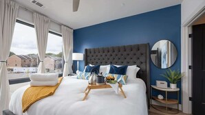 Une chambre d’hôtel moderne avec un grand lit, un miroir rond et une vue sur l’extérieur.