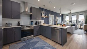 Une cuisine moderne avec des meubles gris, des appareils en acier inoxydable et un îlot central.