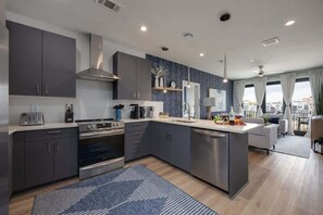 A modern kitchen with grey cabinets, stainless steel appliances, and a central island.