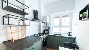 A modern kitchen with a gas stove, oven, and microwave, a wooden ladder, and a window with a view. - Casa Di Cristina in Rome (Rome)