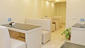 A hotel room with a seating area featuring a table and chairs, a small table with a chair, and a potted plant. - Hotel Nilakantha (Kathmandu)