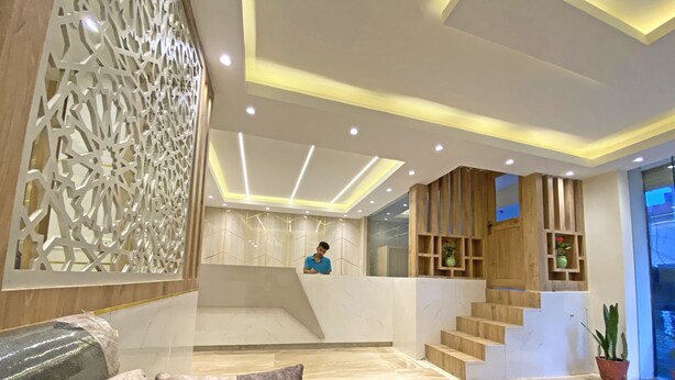 A modern lobby with a marble floor, a reception desk, a staircase, and decorative wooden panels. - Hotel Nilakantha (Kathmandu)