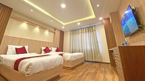 A hotel room with two beds, a TV, and a wooden floor. - Hotel Nilakantha (Kathmandu)