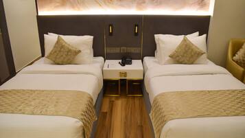 Une chambre d’hôtel avec deux lits, une table de chevet avec un téléphone et un mur décoré d’un motif imitant le marbre.