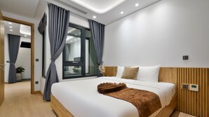 A modern hotel room with a large bed, wooden headboard, and a view of the city through a large window. - The Galaxy Home Apartment Doi Can (Hanoi)