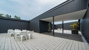 A modern outdoor patio with white plastic furniture and a dark building facade. - LUXE TECH VILLA ASHITOKU (Tatsugo)