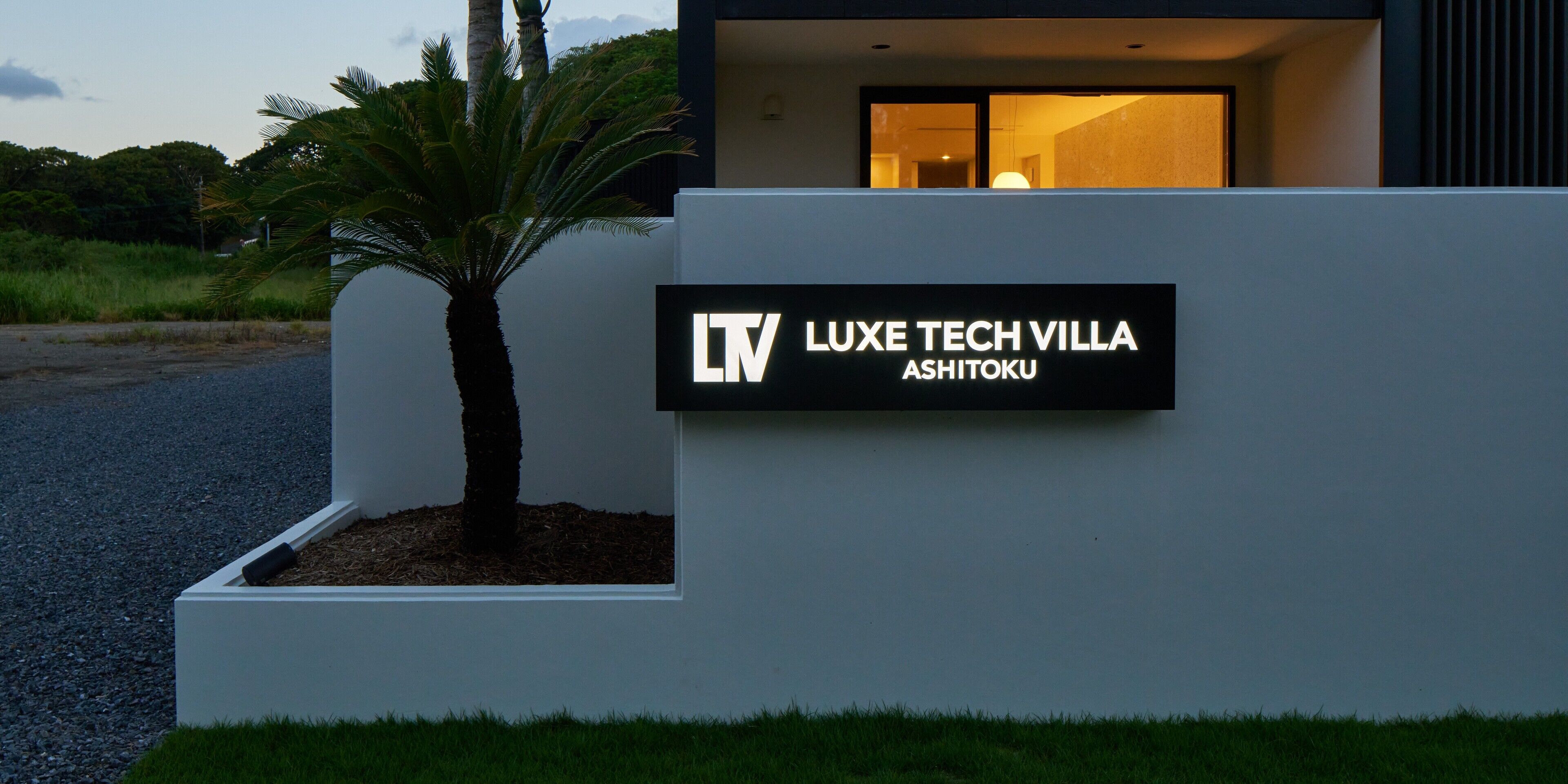 A sign for Luxe Tech Villa Ashitoku with a modern building in the background.
