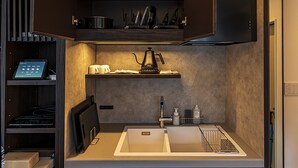 A modern kitchen with a built-in coffee maker, a sink, and a countertop with a kettle and cups. - LUXE TECH VILLA ASHITOKU (Tatsugo)