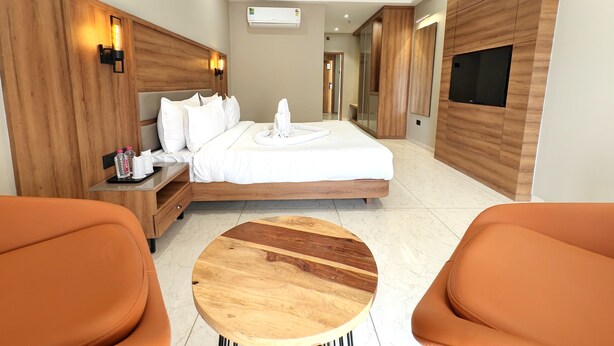 Una habitación de hotel moderna con cama, mesita de noche y una mesa redonda de madera.