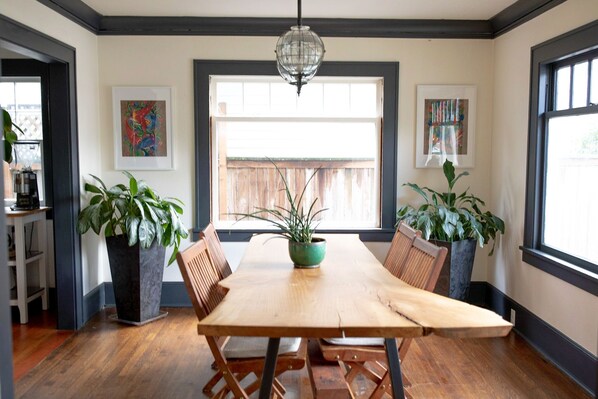 A dining area with a wooden table, chairs, potted plants, and artwork on the walls. - Portland Escape (Portland)