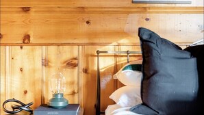 Une pièce de style cabane en bois, avec un lit, une table de chevet dotée d’une lampe et un tableau encadré au mur.
