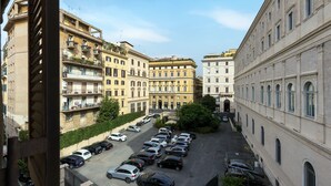 A parking lot with multiple cars, surrounded by multi-story buildings with balconies and windows. - Santa Margherita Design Apartment in Navona (Roma)
