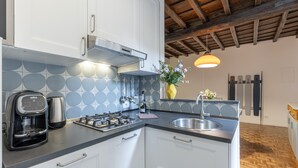 A modern kitchen with white cabinets, a coffee maker, a gas stove, and a sink. - Santa Margherita Design Apartment in Navona (Roma)
