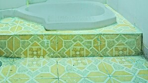 A bathroom with a bathtub, tiled floor, and walls painted in a light teal color. - Hotel O Barito House (Pematangsiantar)