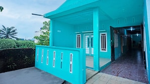 A turquoise building with a covered entrance, a tiled walkway, and a visible door. - Hotel O Barito House (Pematangsiantar)