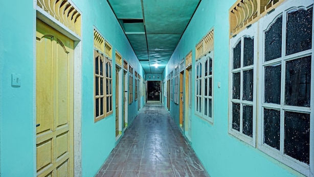 A corridor with teal walls, yellow doors, and windows with white frames. - Hotel O Barito House (Pematangsiantar)