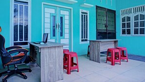 A room with a desk, computer, and two red stools. - Hotel O Barito House (Pematangsiantar)