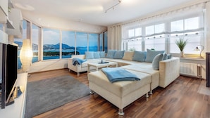 A modern living room with a large window, a sofa set, a coffee table, and a TV.