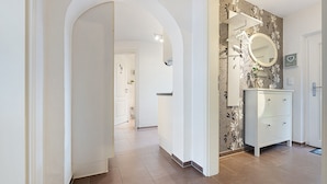 A hallway with a white door, a white cabinet with drawers, and a mirror above the cabinet.