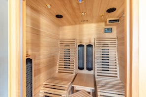 Un sauna avec des bancs en bois, une table et un panneau de commande.