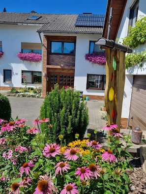 Un bâtiment doté d’un toit recouvert de tuiles, de panneaux solaires et de jardinières.