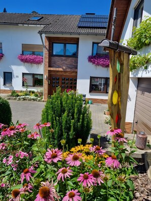 Um edifício com telhado em telhas, painéis solares e caixas com flores.