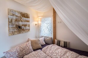 Ein Schlafzimmer mit Bett, Kissen, einer Wandlampe und einem Wandbild.