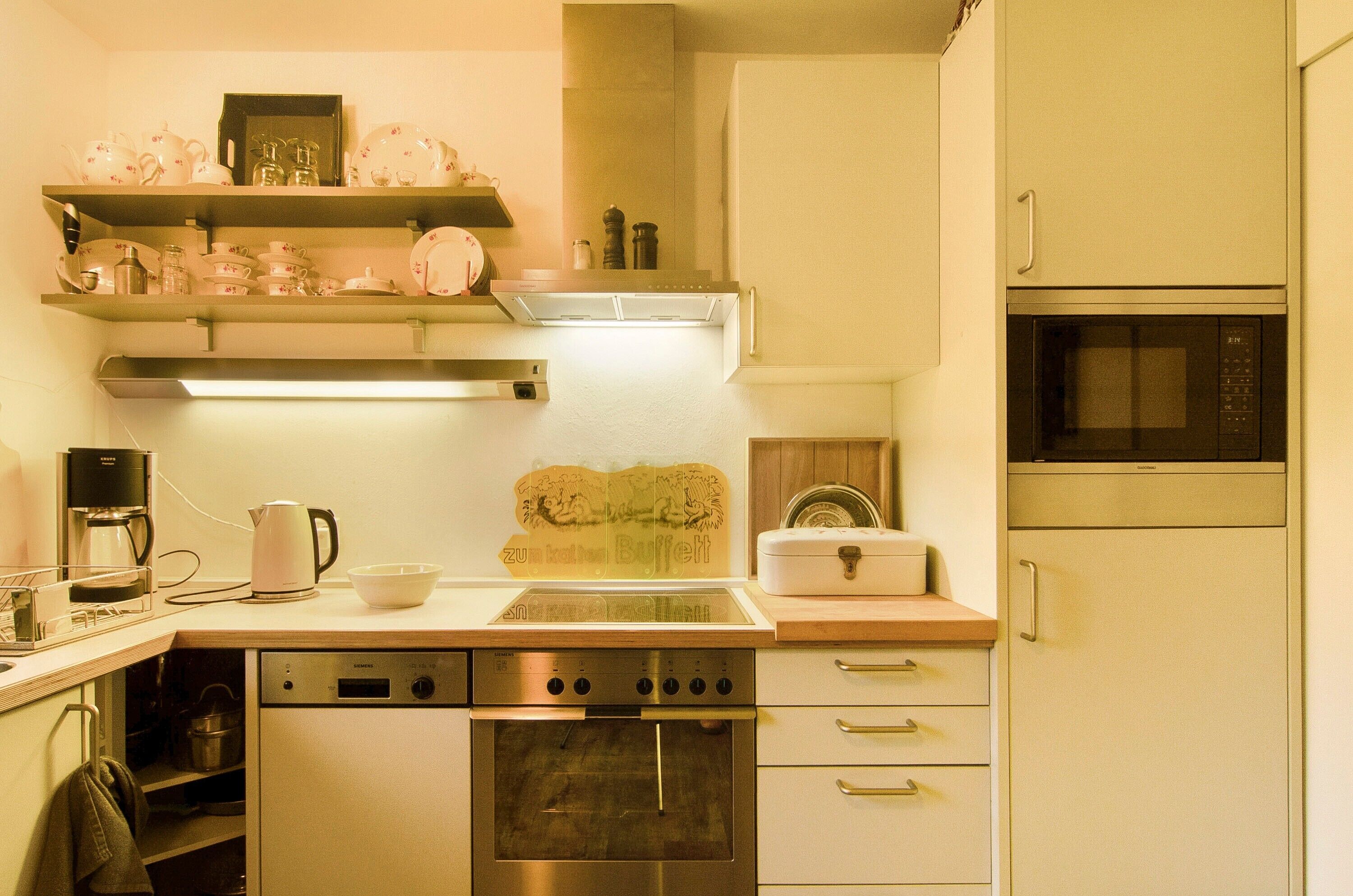A kitchen with a dishwasher, oven, microwave, and a coffee maker.
