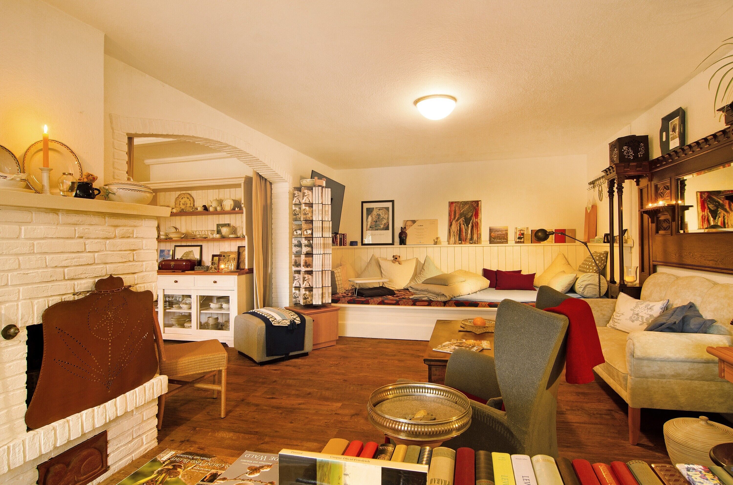 A cozy living room with a fireplace, a bookshelf, a sofa, and a dining table.