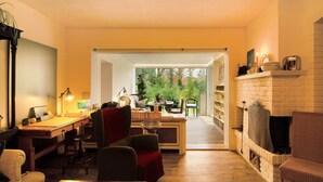 Una sala de estar moderna con un escritorio, sillas, una chimenea y vistas a zonas verdes.