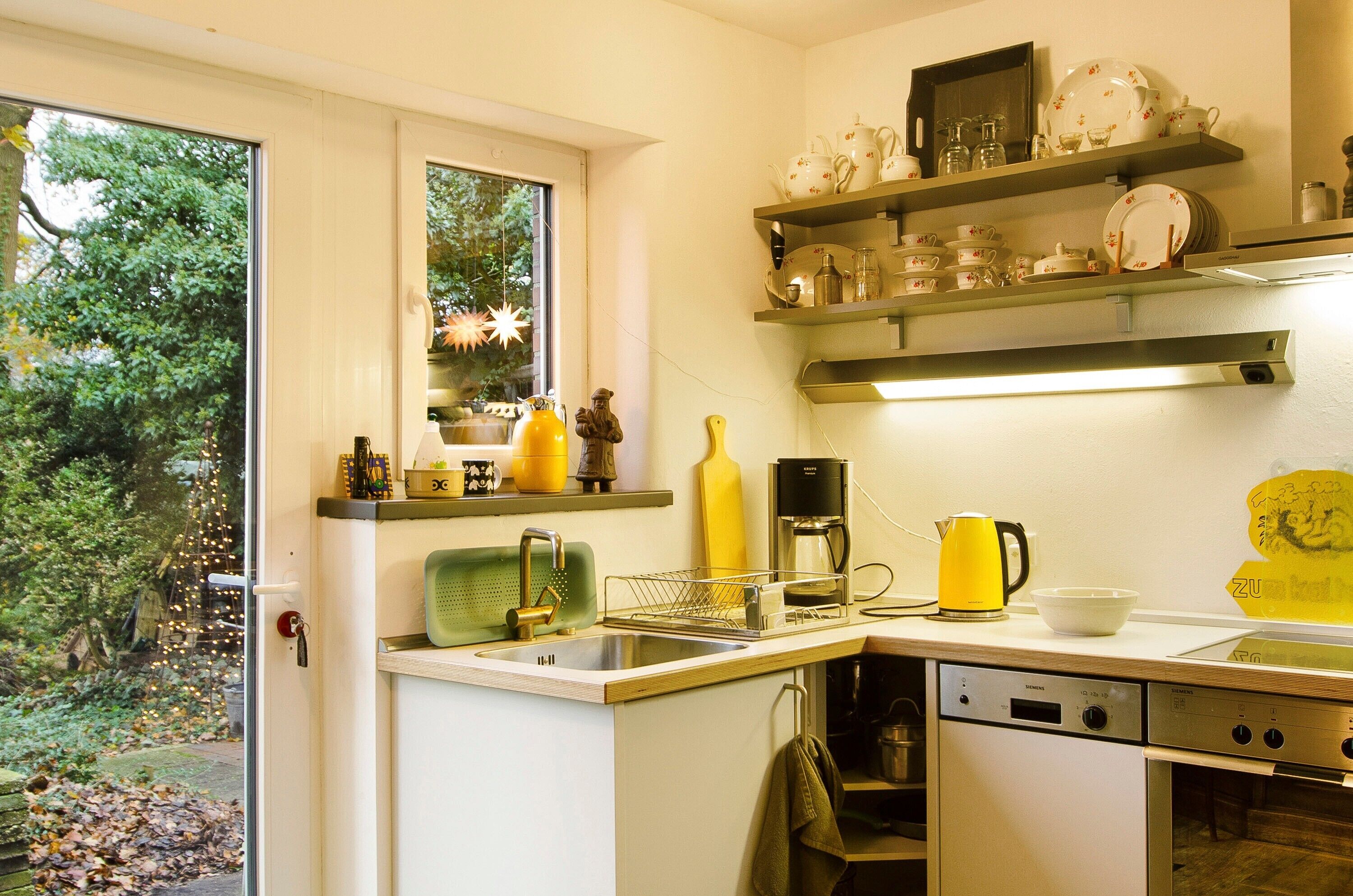 Eine Küche mit Fenster, eingebauten Regalen, einer Kaffeemaschine und einem Geschirrspüler.