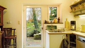 Una cocina con ventana, un lavamanos y una cafetera.