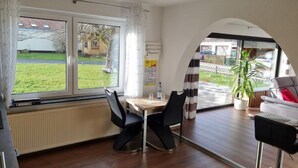A dining area with a table, chairs, and a view of a garden through a window.