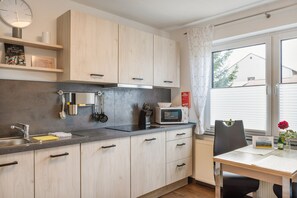 Eine moderne Küche mit Holzausstattung, einer Mikrowelle und einem Essbereich mit Tisch und Stühlen.