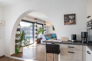 Eine moderne Küche mit Kaffeemaschine, einer Couch und Blick durch einen Bogen.