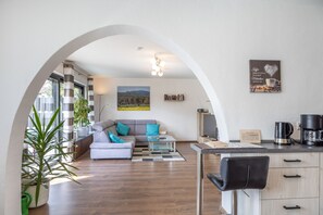Een moderne woonkamer met een bank, salontafel en uitzicht op het omliggende landschap via een boogvormige doorgang.