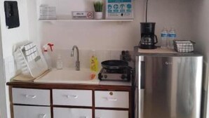 A compact kitchenette with a microwave, a coffee maker, and a refrigerator.