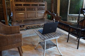 A wooden bench with a laptop on a wicker table.