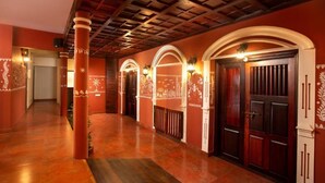 A hallway with wooden columns, arched doorways, and decorative wall patterns. - Ananda Cherai (Kochi)