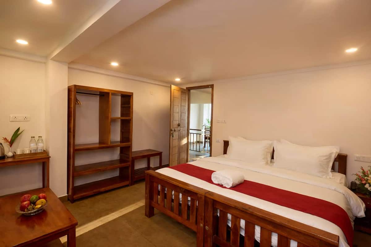 A bedroom with a bed, wooden wardrobe, bedside table, and a small table with fruit.