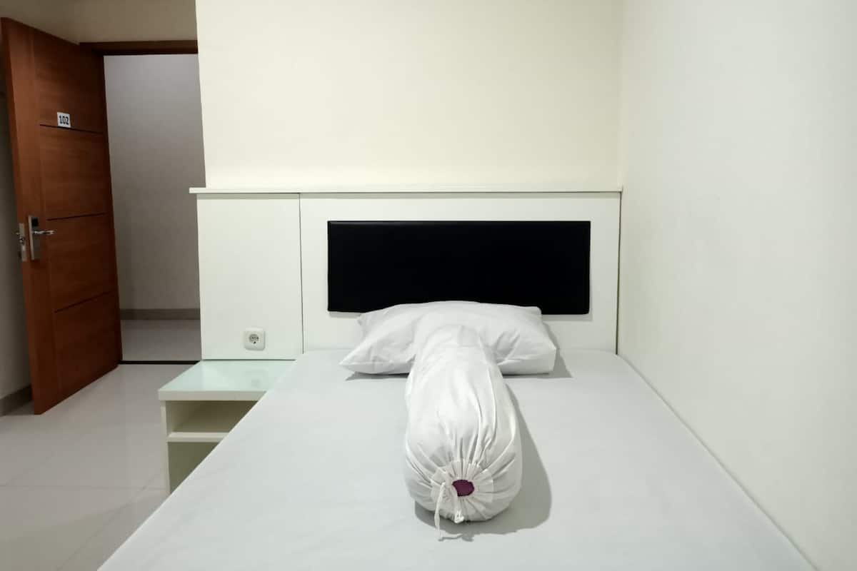 Una habitación de hotel con una cama, una puerta de madera y una mesita de noche.