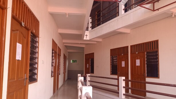 A multi-level corridor with wooden doors and windows, a tiled floor, and a metal railing on the upper level. - Hotel O Lourdes Blessing Hill (Manado)
