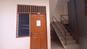 A wooden door with a window, a staircase with metal railings, and a number sign above the door. - Hotel O Lourdes Blessing Hill (Manado)