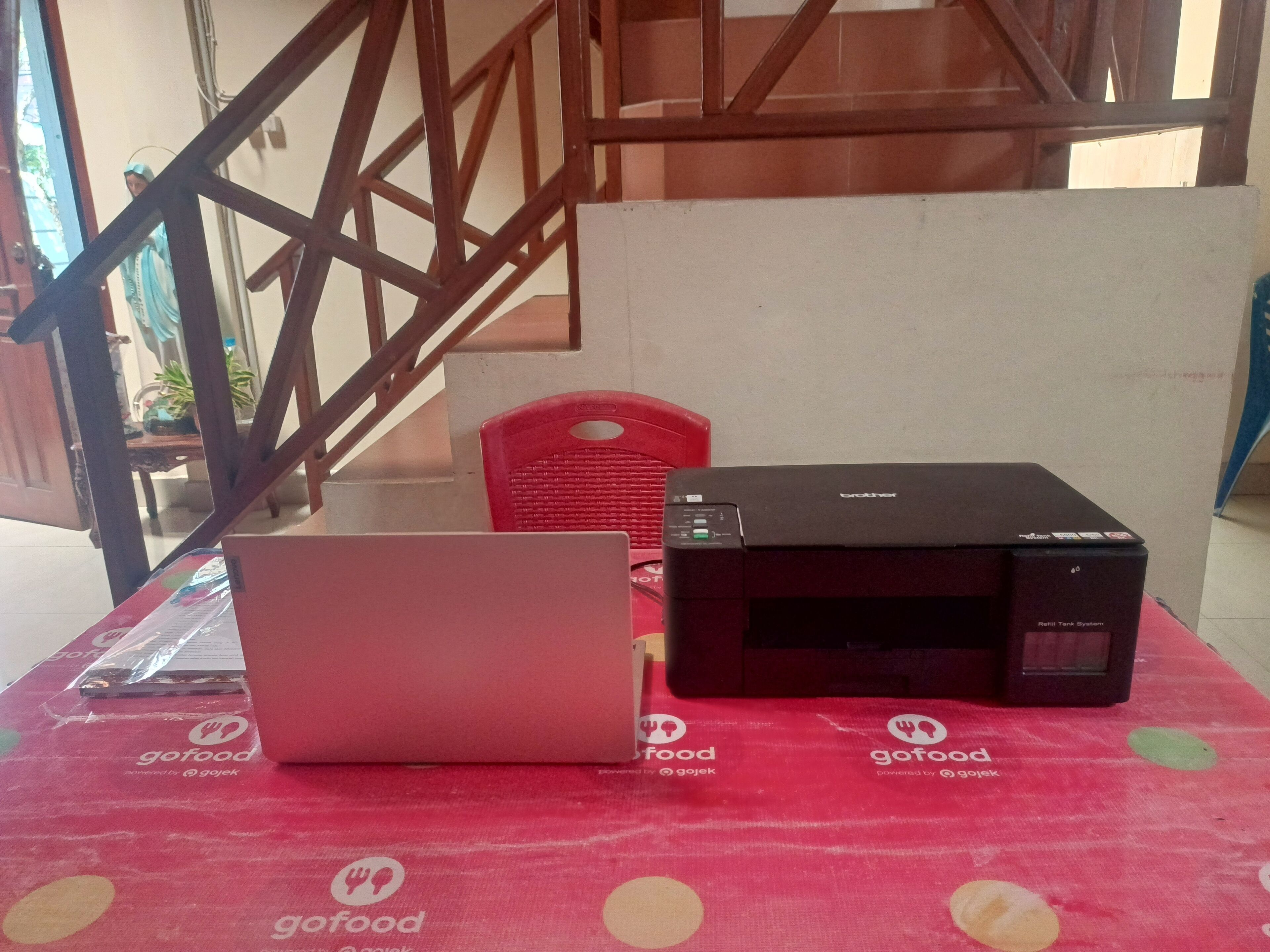 Ein Laptop und ein Brother-Drucker stehen auf einem Tisch mit einer roten Tischdecke.