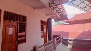 A building with a balcony, a wooden door with a number, and a window with bars. - Hotel O Lourdes Blessing Hill (Manado)