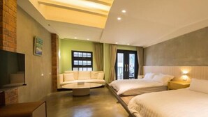 Una camera d'albergo con un divano, due letti, una televisione e un balcone.