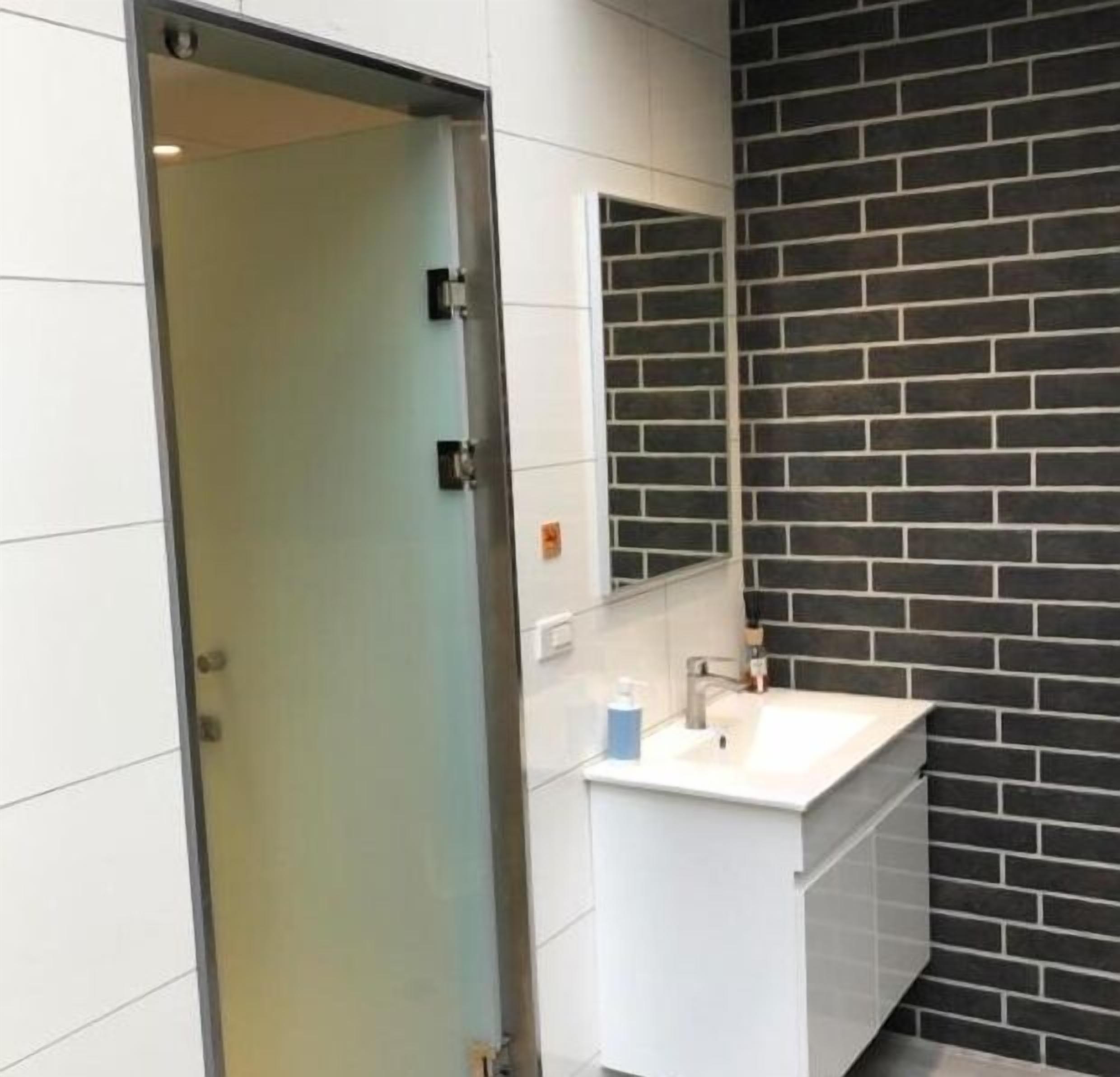A bathroom with a white sink, a mirror, and a black brick wall.