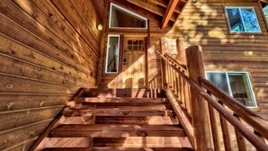 A wooden staircase leading to a door with a window above it. - Donner Adventure Lodge: Pet Friendly, Games, Bunks (Truckee)