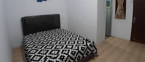 Un dormitorio con cama, aire acondicionado de pared y una puerta con cortina.