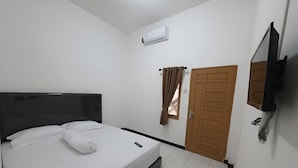 Une chambre à coucher comprenant un lit, un téléviseur fixé au mur, une porte et un appareil de climatisation.